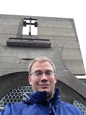 Dr. Kiel in front of the bell banner at Saint John’s Abbey in Minnesota