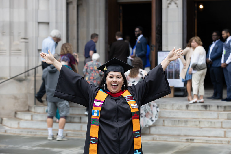 Princeton Theological Seminary female student holds arms in the air to celebrate graduation