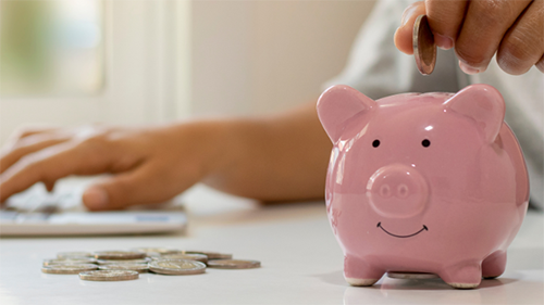 A close up of a man putting quarters into a piggy bank