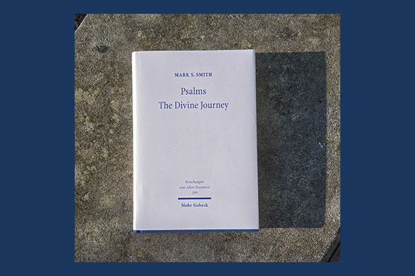 photo of Mark S. Smith's book "Psalms - the divine journey: collected essays (1988-2026)" in the sun casting a shadow on a stone wall by Wright Library, Princeton Theological Seminary